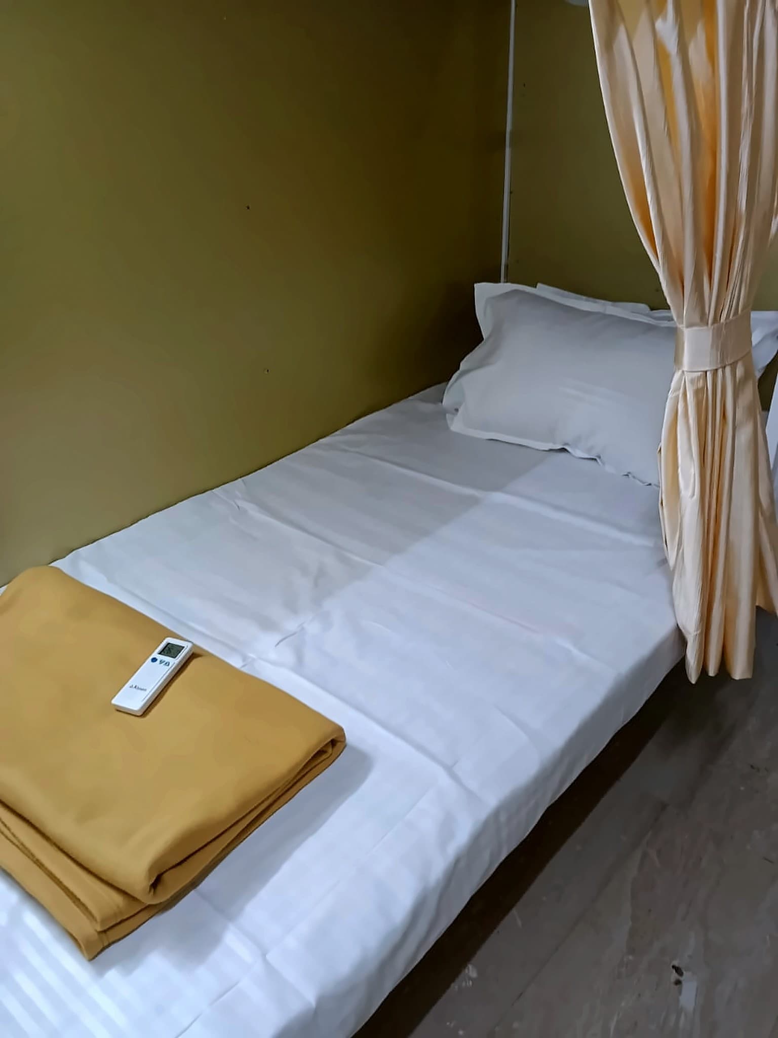 A SNOOZ capsule berth with fresh linen, a blanket and an AC remote